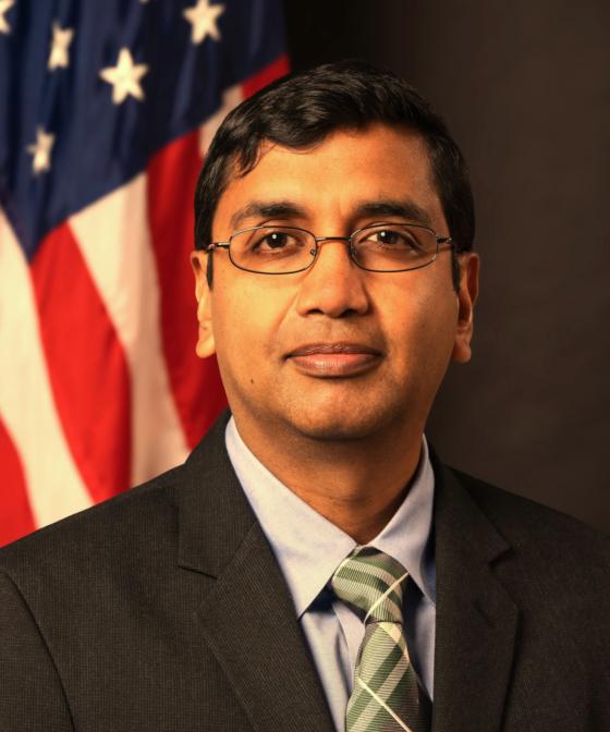 Man in suit in front of flag