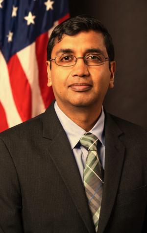 Man in suit in front of flag